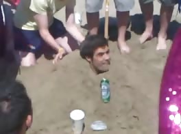 Rugby lads piss hzaing a mate at beach.  
